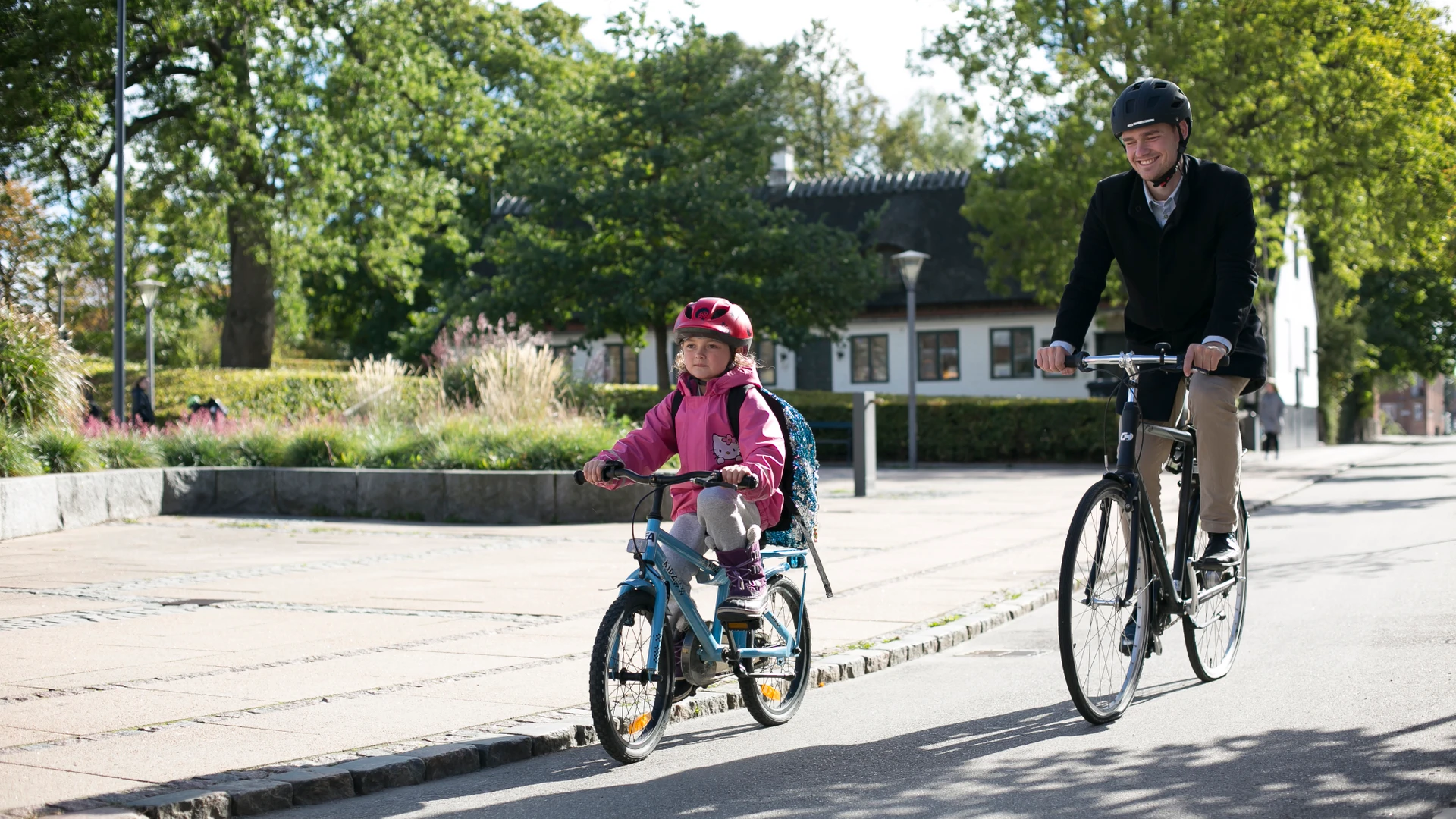 En far og en datter cykler, på vej i skole.